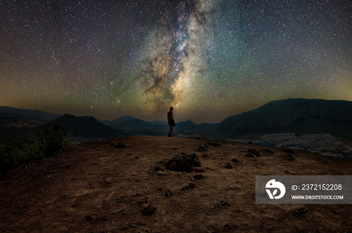一个人站在山顶上观看美丽的银河。