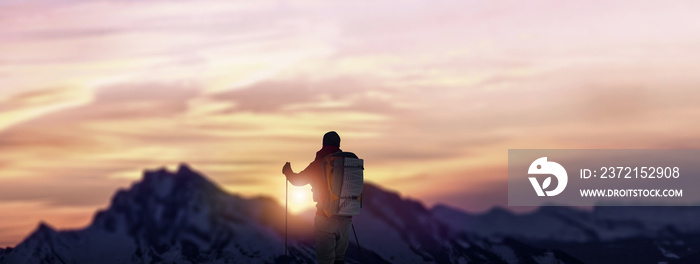 Man is standing on the snowy mountains at sunset.