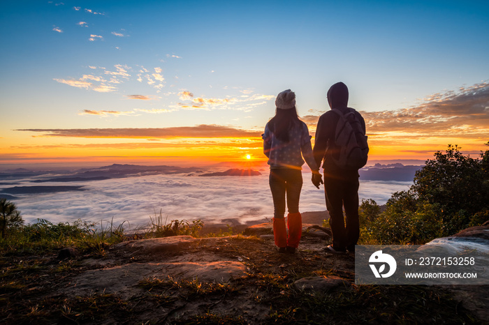 Young couple watching the sun rise from top of mountain