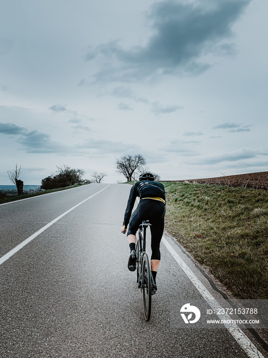 骑自行车的人在秋天沿着公路骑行。在多云的秋天骑公路自行车。