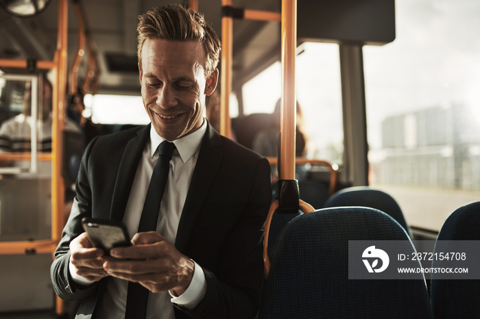 微笑的年轻商人站在公交车上发送短信
