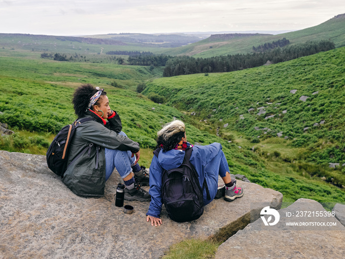 Female hikers sitting on rocks and looking at landscape