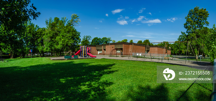 Panorama of a small brick school building and playground