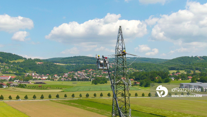 DRONE: Electricians on a boom lift lining up high voltage cables on a new tower.