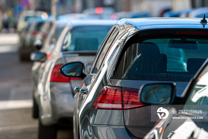 rows of different cars parked along the roadside in crowded city