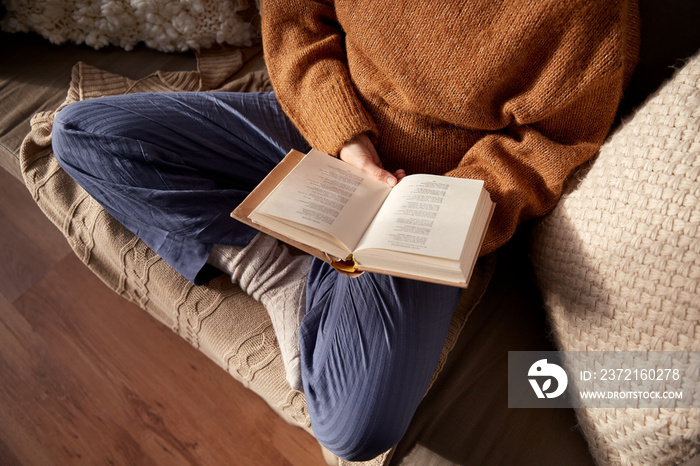 people, season and leisure concept - close up of woman in warm sweater reading book at home