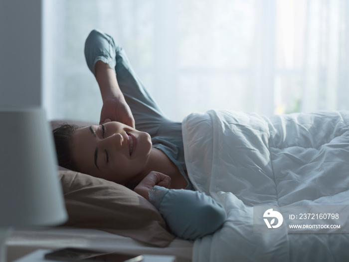 Happy relaxed woman waking up early in the morning