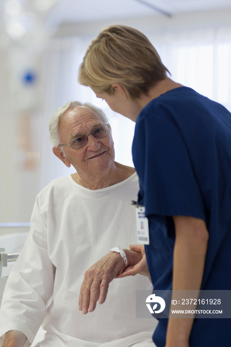 Caring nurse checking on senior patient in hospital room