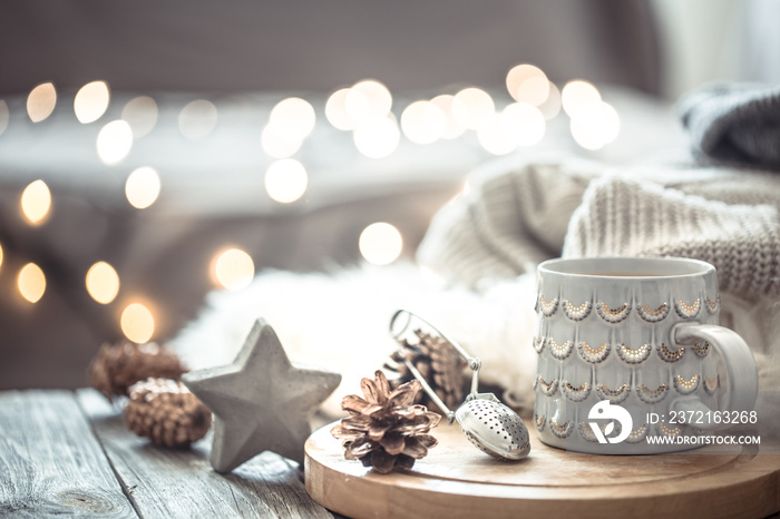 Coffee cup over Christmas lights bokeh in home on wooden table with sweater on a background and deco