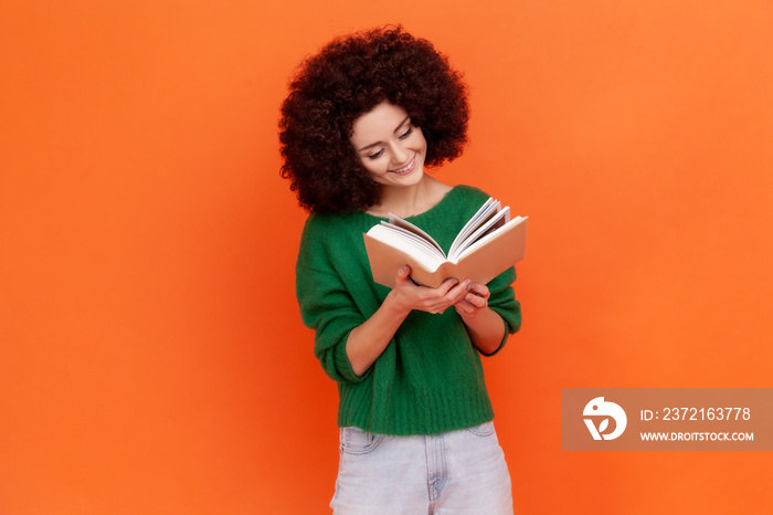 Happy smiling woman with Afro hairstyle wearing green casual style sweater reading book with interes