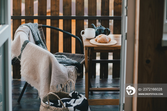 在木制乡村小屋舒适的阳台上享用热茶和羊角面包的秋季早餐。秋季气氛