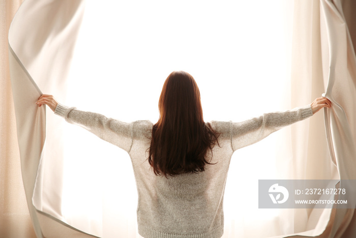 Girl opening curtains