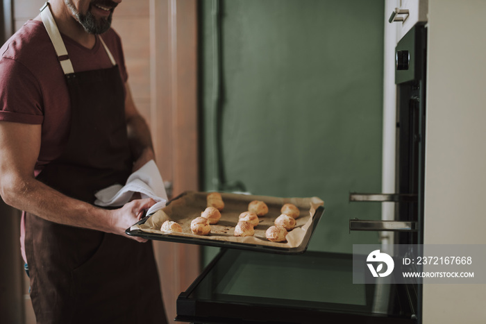 Close up of hot baking pan in hands of smiling man