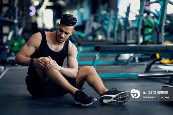 Sport Trauma. Young Arab Male Athlete Touching His Hurted Knee At Gym