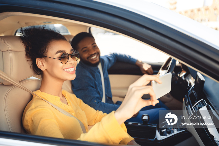 Road trip. Happy couple taking selfie in car