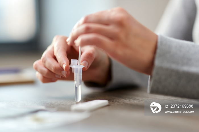 medicine, self testing and pandemic concept - hands of woman making coronavirus test and stirring sw