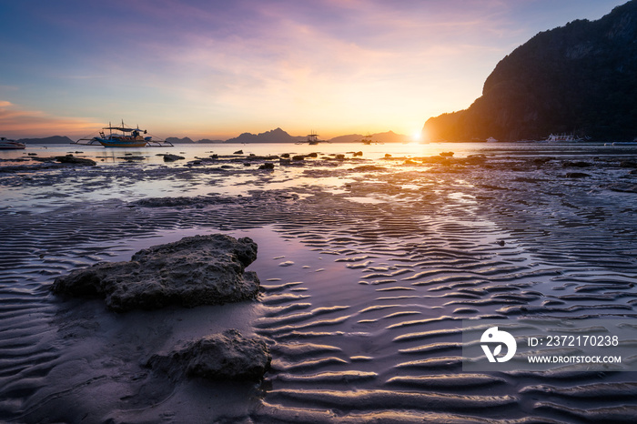 Tropical beach in ebb time low tide on sunset. Mudflats and sun reflections at the golden hour. moun