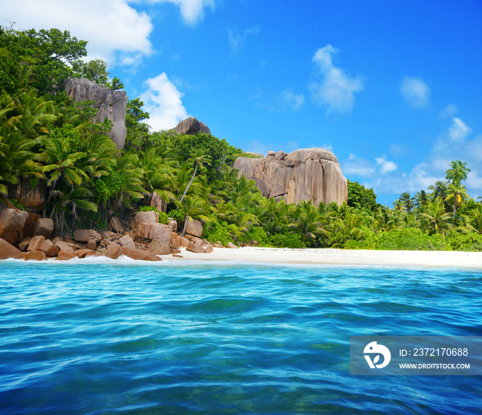 Granite rocks and coconut palm trees on sand beach of the island Grande Soeur near La Digue, Indian 