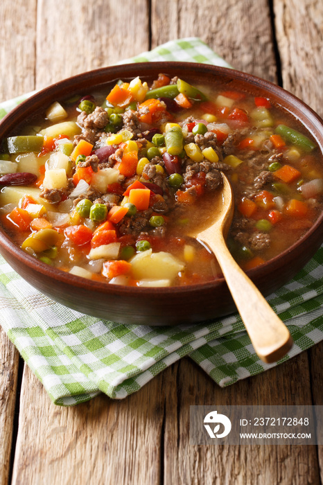 American hamburger soup with ground beef and mix of vegetables close-up on the table. vertical