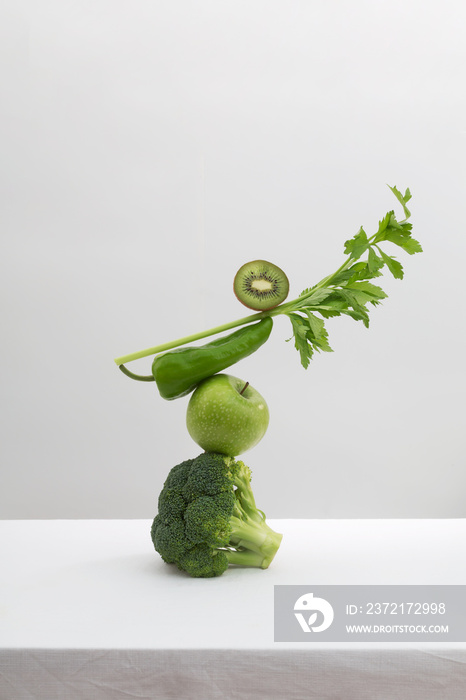 白色餐桌上的新鲜绿色蔬菜和水果。均衡漂浮食物