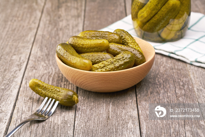 Pickles in a wooden bowl. Preserved cucumbers in bowl on a wooden table, selective focus.