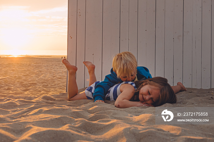 siblings play happily together on a sandy beach at sunset. travel destination and family vacation co