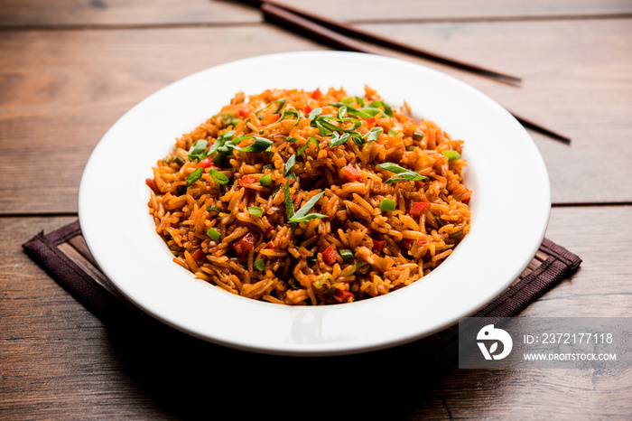 Schezwan Fried Rice Masala is a popular indo-chinese food served in a plate or bowl with chopsticks.