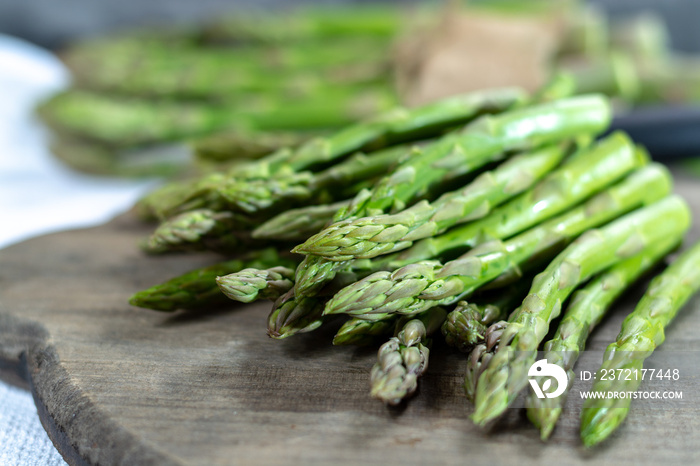 Fresh raw green asparagus vegetable on wooden plank, close up