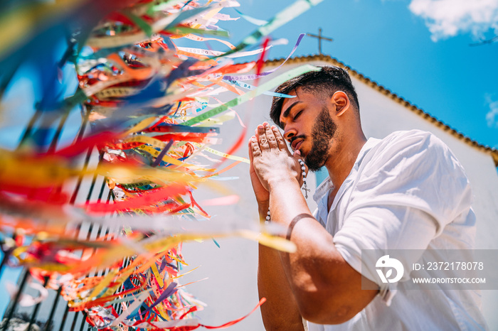 Latin American man placing an order with Brazilian tapes on the fence of a church in Arraial dAjuda