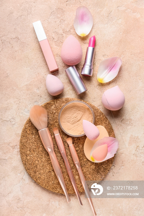 Composition with makeup sponges, brushes, cosmetics and petals on color background