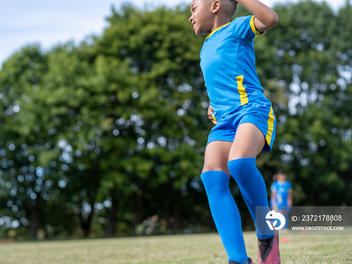 男孩（8-9岁）穿着制服在足球场上练习