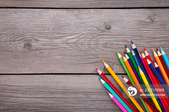 Many different colored pencils on grey wooden background