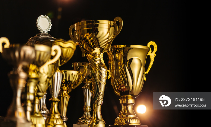 Group of the golden trophies in sparkling light on the dark background.