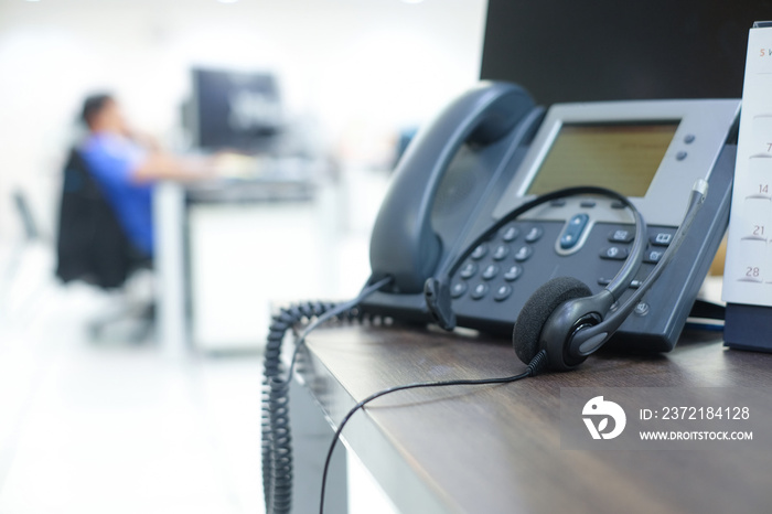 close up focus on telephone with blurred of call center employee man working in operation room for c