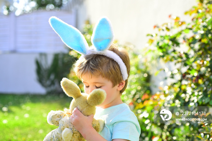 Easter boy with toy. Sweet kid baby hugging a teddy bear. The boy wears bunny ears for the holiday.