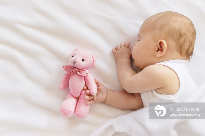 Baby sleeps with a teddy bear on a white background. Selective focus.