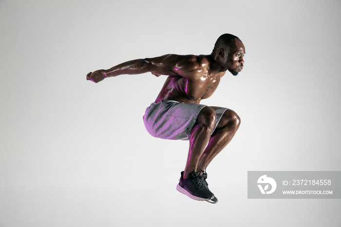 Young african-american bodybuilder training over grey background