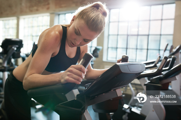 Fit young female exercising on gym bike