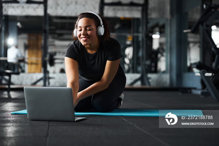 快乐的年轻女性在锻炼时用笔记本电脑上网