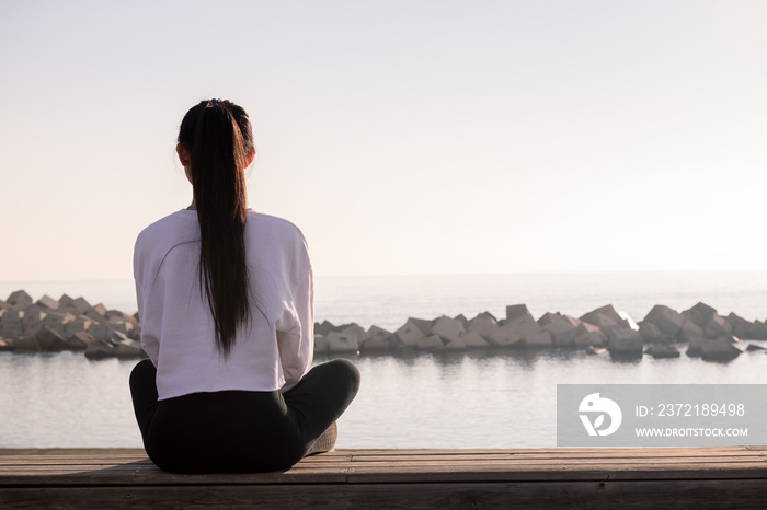 rear view of a young woman sitting meditating