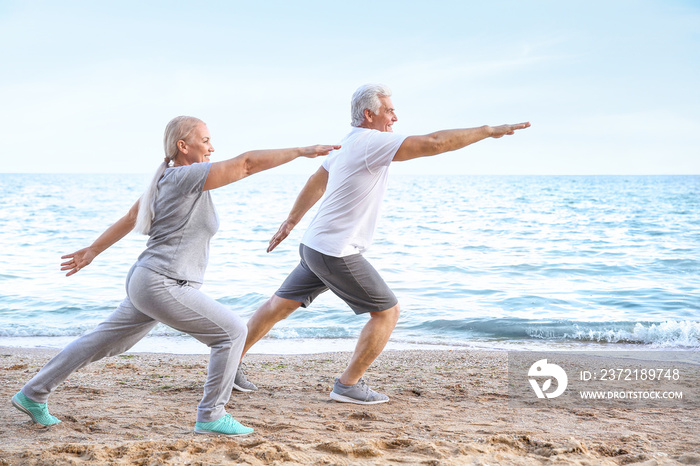 Mature couple practicing yoga at sea resort