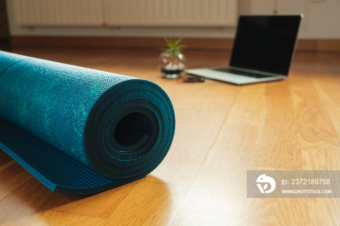 Yoga mat and laptop prepared for an online yoga class at home. Selective focus, background.