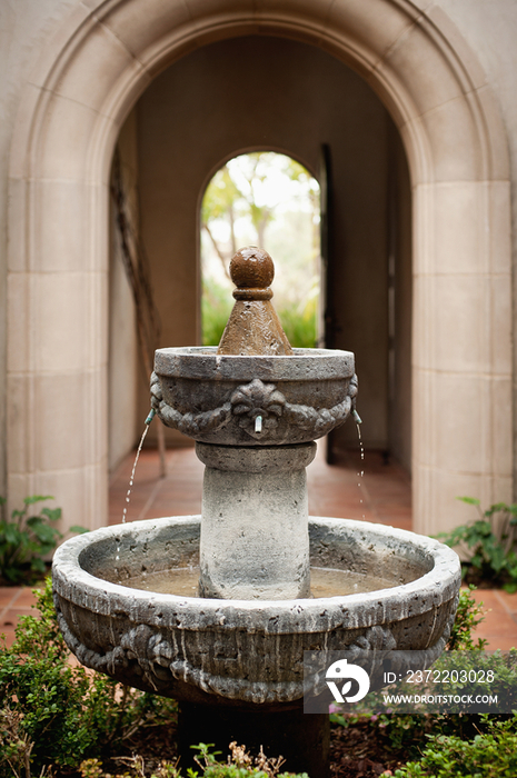 View of plants around fountain at courtyard against arched structure