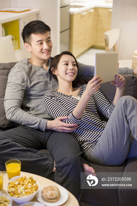 年轻情侣在客厅沙发上使用平板电脑