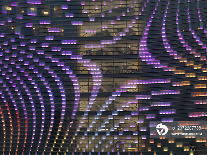 Low angle view of illuminated hotel building with purple lighting at dusk