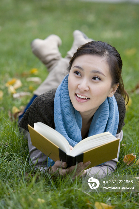 青年女子趴在草地上看书