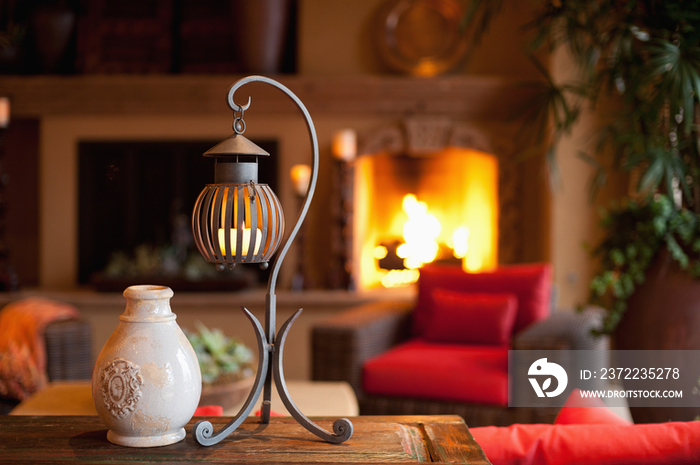 Pot with candle lantern on table against lit fireplace in living room at home; Scottsdale; USA