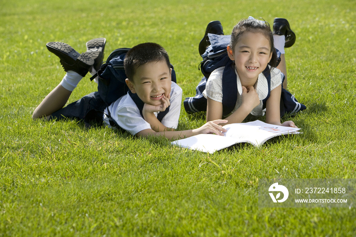 两个在草地上看书的小学生