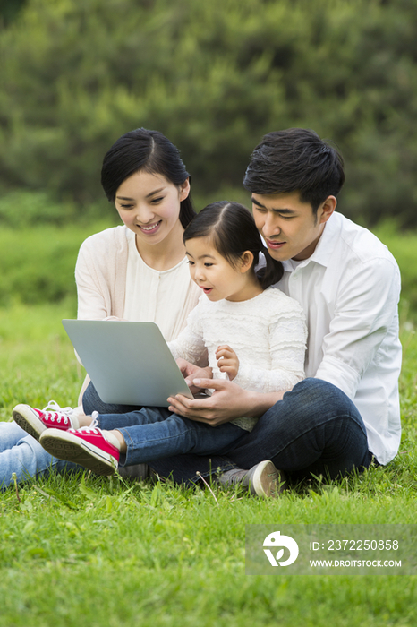 快乐的一家人在草地上玩电脑