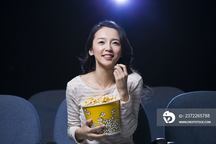 年轻女子边看电影边吃爆米花